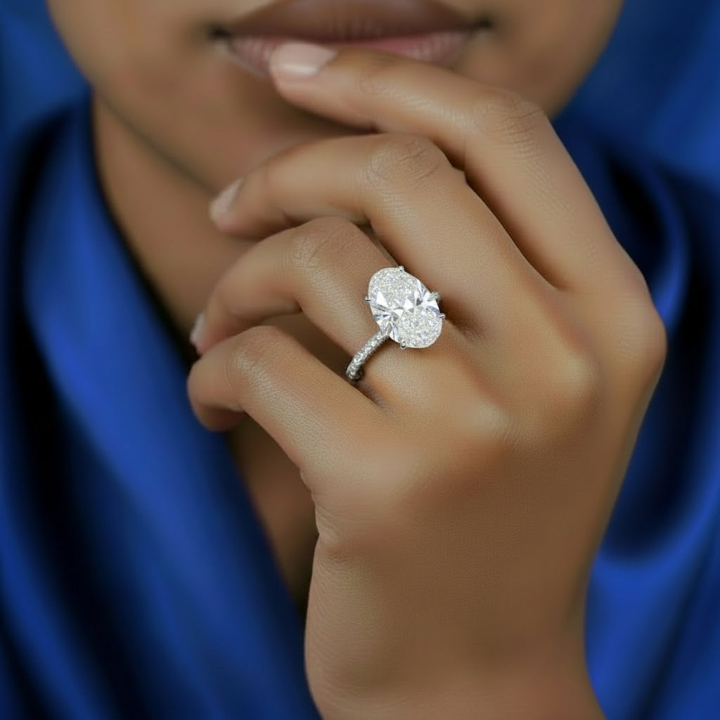 Close-up of a hand wearing a diamond ring with a blue fabric background